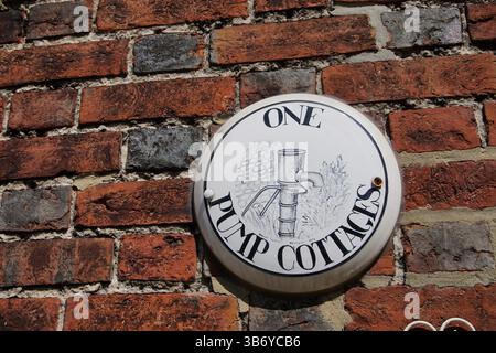 Handgemalte Namensschild „One Pump Cottages“ an einer traditionellen roten Backsteinmauer, ländliches England. Rye, Sussex, England Stockfoto