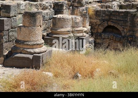 Steinsäulenbasen und römische Mauerwerke an der archäologischen Stätte Beit She’an in Israel, die Basaltblöcke und verwitterten Kalkstein zeigen. Stockfoto