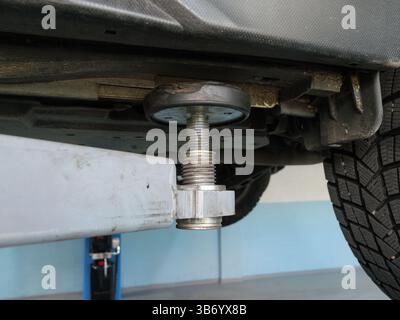 Großaufnahme einer Hebebühne, die ein Fahrzeug während der Wartungsarbeiten in einer professionellen Autowerkstatt hebt Stockfoto