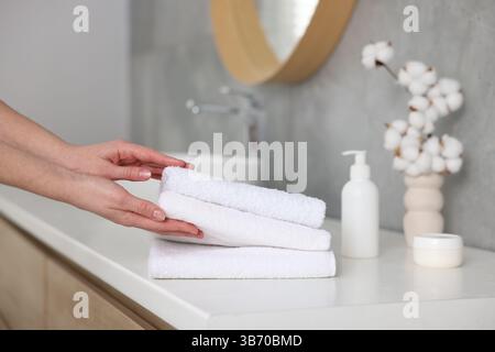 Frau, die saubere Handtücher vom Waschtisch im Bad nahm, Nahaufnahme Stockfoto