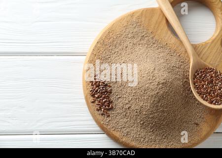 Leinsamenmehl und Löffel mit Samen auf weißem Holztisch, Draufsicht. Leerzeichen für Text Stockfoto