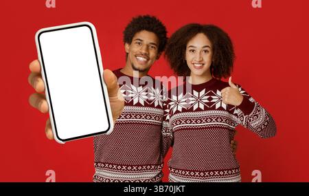 Frohe Weihnachten und frohes neues Jahr. Das fröhliche junge afroamerikanische Paar zeigt die Daumen hoch Stockfoto