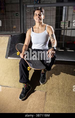 Ein 26-jähriges brasilianisches Mädchen, das auf Deck sitzt und ihren Schlittschuh hält. Stockfoto
