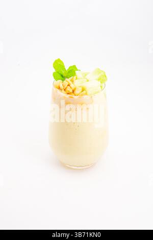 Cremiger Bananen-Smoothie mit Müsliflocken und frischer Minze serviert in klarem Glas auf weißem Hintergrund. Hochwertige Fotos Stockfoto