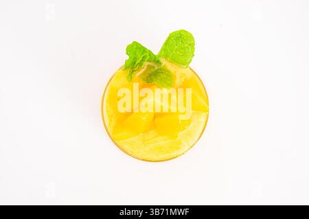 Mango- oder Pfirsich-Smoothie mit Eis- oder Fruchtwürfeln in transparentem Glas serviert und mit frischen Minzblättern auf weißem Hintergrund garniert. Hochwertige Fotos Stockfoto
