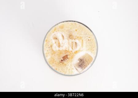 Eiskaffee mit Sahne und Eiswürfeln serviert in hohem, klarem Glas mit schaumiger Oberseite, fotografiert auf weißem Hintergrund. Hochwertige Fotos Stockfoto