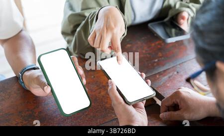 Hände männlicher und weiblicher Freunde mit Handys auf dem Tisch im Café. Der Blogger zeigt mit dem Finger auf den Telefonbildschirm und zeigt den neuen Beitrag. Gemeinsame Nutzung der s Stockfoto