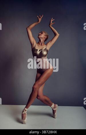 Eine Ballerina in einem Body zeigt Plastizität, indem sie geht und ihre Hände hochhält Stockfoto
