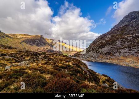 Llyn Idwal liegt am Fuße von schroffen Geröllhängen und windgepeitschten Mooren unter einem dramatischen Ufer von Cumulus-Wolken Stockfoto