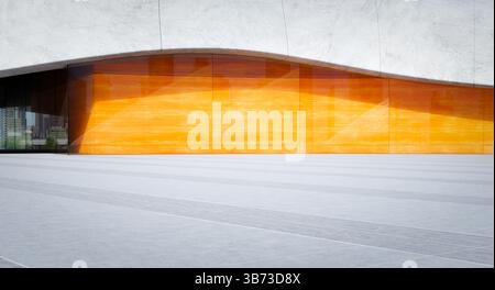Orangefarbene Glasfassade eines modernen Gebäudes mit Betonwand und Fliesenboden, die Sonnenlicht reflektieren. 3D-Rendering Stockfoto