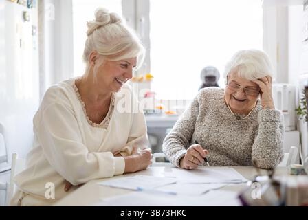Frau, die ihrer älteren Mutter hilft, Finanzdokumente zu erstellen Stockfoto