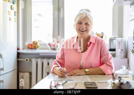 Senior Frau, die zu Hause Finanzberichte ausfüllt Stockfoto