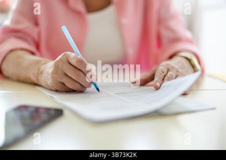 Senior Frau, die zu Hause Finanzberichte ausfüllt Stockfoto