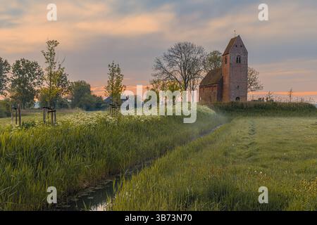 Ein Frühlingssonnenaufgang in der alten historischen mauritischen Kirche im kleinen Dorf Marsum im nördlichen Teil der Niederlande in der Provinz Gr Stockfoto