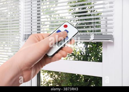 Frau, die die Jalousien im Zimmer fernbediente, Nahaufnahme Stockfoto