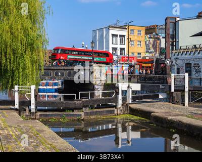 London, Vereinigtes Königreich - 28. April 2025: Eine pulsierende urbane Szene mit einem roten Doppeldeckerbus, der eine Regent-Kanalbrücke in einem lebhaften Stadtgebiet überquert Stockfoto