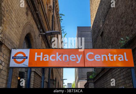 London, Großbritannien - 28. April 2025: Schild für Hackney Central Overground Station mit Backsteinhäusern. Stockfoto