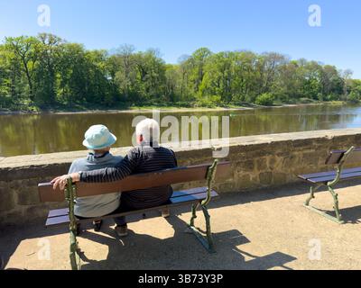 Pensioniertes Ehepaar, das im Frühling bei schönem Wetter am Elbufer sitzt Stockfoto