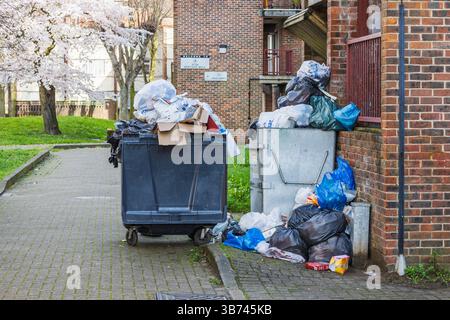 Überfüllte Mülltonnen mit verstreuten Müllsäcken in städtischen Gassen Stockfoto