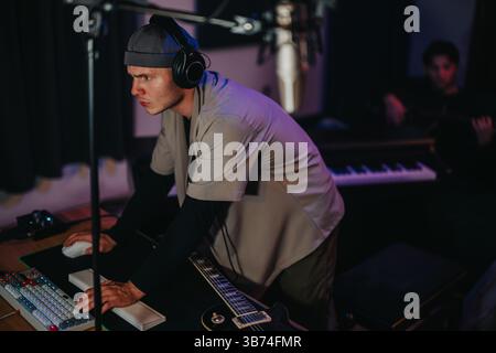 Fokussierter Musikproduzent, der in einem modernen Aufnahmestudio mit digitaler Ausrüstung arbeitet Stockfoto