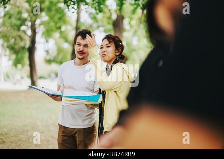 Multikulturelle Studenten, die gemeinsam in einer ruhigen Parklandschaft studieren Stockfoto