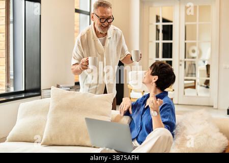 Ein fröhliches Paar genießt gemeinsam Kaffee, während es zu Hause lebhafte Gespräche führt. Stockfoto
