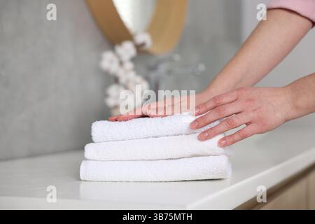 Frau, die saubere Handtücher vom Waschtisch im Bad nahm, Nahaufnahme Stockfoto