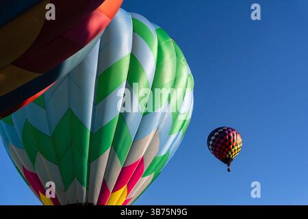 Leuchtende Luftballons aller Formen und Farben schweben in den klaren blauen Himmel und erfüllen die Luft bei einem klaren Ballonfest im Herbst mit Spannung. Die sc Stockfoto
