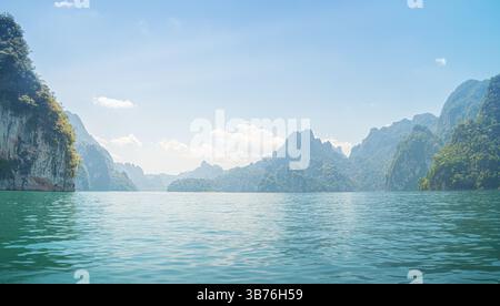 Der Cheow Lan Lake zeigt sein ruhiges Wasser, das das lebhafte Grün der umliegenden Kalksteinklippen und Berge reflektiert. Befindet sich in Khao Sok National Stockfoto