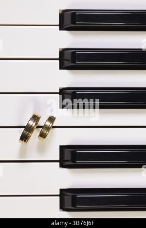 Detail der Klaviertastatur und Trauringe Stockfoto