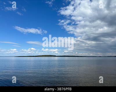 Eine atemberaubende Landschaft eines ruhigen Sees mit leuchtend blauem Himmel und flauschigen Wolken. Stockfoto