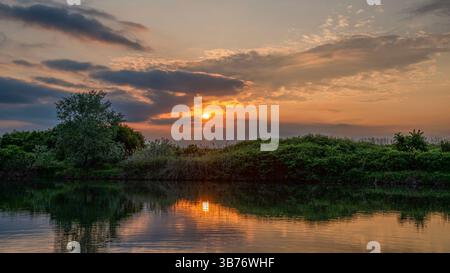 Wunderschöne Naturlandschaft mit dramatischem Sonnenuntergang über dem kleinen See Stockfoto