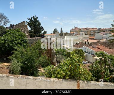 Die Mauern des Schlosses Tavira mit Blick auf die Altstadt mit einem Baum voller Orangen darunter. Stockfoto