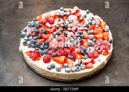 Köstlicher Käsekuchen mit Erdbeeren, Himbeeren und Heidelbeeren mit Puderzucker, perfekt für Dessertmenüs oder Food Blogs. Stockfoto