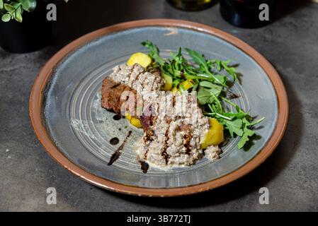 Überzogenes Gericht mit gegrillten Rindfleischmedaillons, garniert mit cremiger Pilzsauce, serviert mit Kartoffeln und frischem Rucola-Gemüse. Stockfoto