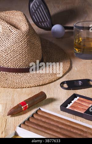 Siesta: Zigarre, Strohhut, Scotch Whiskey und Golffahrer auf einem Holztisch Stockfoto