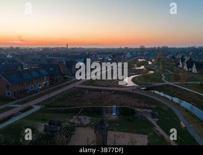 Malerischer Blick aus der Vogelperspektive bei Sonnenaufgang, mit bunten Dächern, gewundenen Kanälen und fernem Horizont. Stadt Nijkerk, Niederlande. Stockfoto