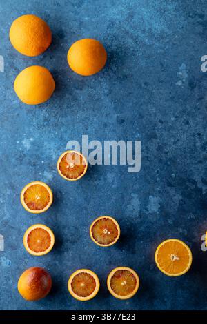 Ganze und geschnittene Orangen auf blauem Hintergrund Stockfoto