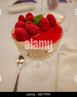 Creme Brulee bedeckt mit rotem Pulver und Himbeeren und serviert in einem Glasbecher. Nahaufnahme eines Dessertfotos Stockfoto