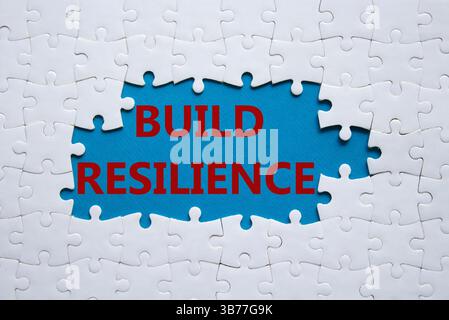 Symbol für Belastbarkeit erstellen. Weißes Puzzle mit Wörtern schafft Widerstandsfähigkeit. Wunderschöner blauer Hintergrund. Business- und Build Resilience-Konzept. Kopierbereich. Stockfoto