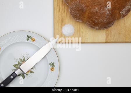 Frisch gebackenes Brot mit Brotschneidemesser, sehr alter Teller auf dem Holztisch mit Stockfoto