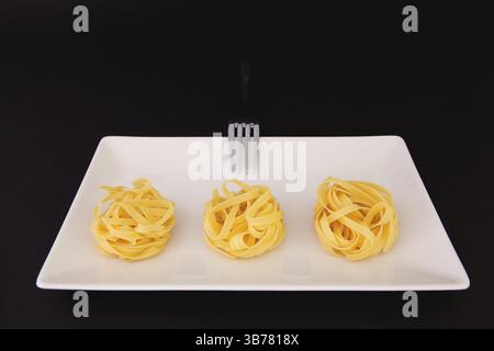 Nudeln aus rostfreiem Stahl und Tagliatelle auf der weißen Platte. Diät-Mittagessen Stockfoto
