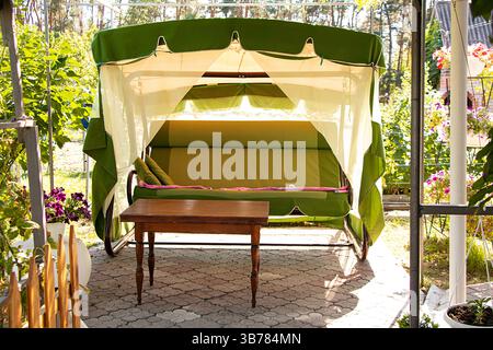 Sommer Hütte Schaukel mit einem Baldachin zwischen Blumen im Sommer im Ferienhaus in der Ukraine, Hütte Schaukel, Ort zum Entspannen Stockfoto
