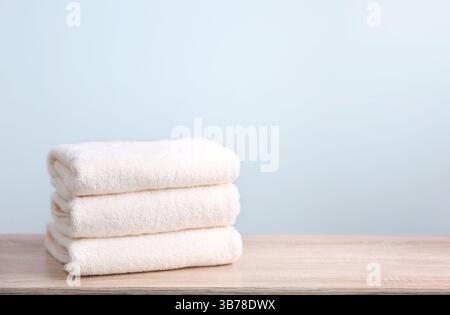 Stapel von weißen Frottierhandtüchern auf hölzernem Tisch mit leerem Hintergrund. Stockfoto