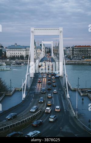 Blick auf Autos, die am Abend auf der Elisabeth-Brücke über die Donau in Budapest vorbeifahren. Stockfoto