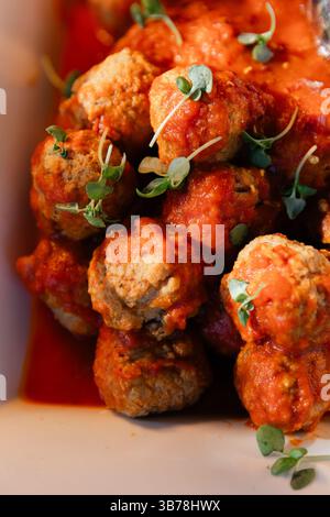 Köstliche Fleischbällchen, die in einer herzhaften Tomatensauce mit frischen Kräutern köcheln, perfekt für ein gemütliches Abendessen. Stockfoto
