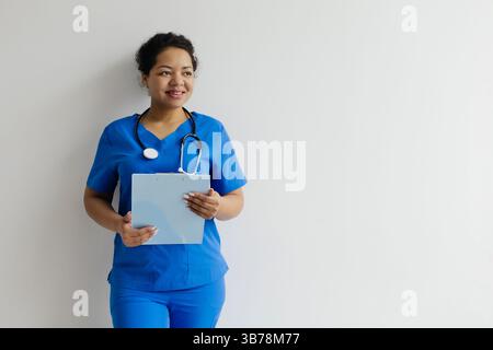 Porträt einer lächelnden schwarzen Ärztin in blauen Schutten mit Klemmbrett Stockfoto