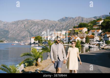 Ein liebevolles Paar geht mit Händen am Damm der Altstadt von Perast entlang. Stockfoto