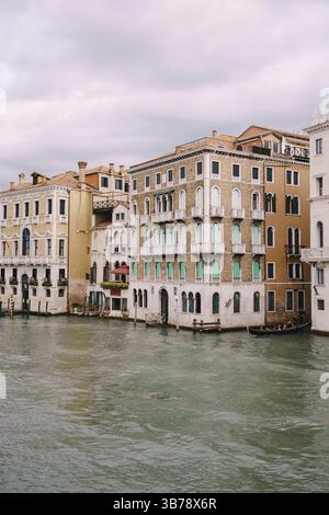 Eine Gondel mit Touristen segelt entlang des Canal Grande zwischen den Fassaden venezianischer Häuser, die auf dem Wasser in Venedig, Italien, Europa stehen Stockfoto