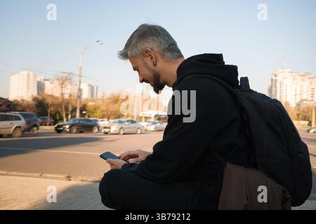 Mann, der bei Sonnenaufgang im Freien mit einem Rucksack sitzt Stockfoto